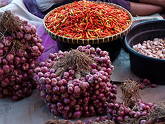 Large bowl of chilis and piles of shallots in market